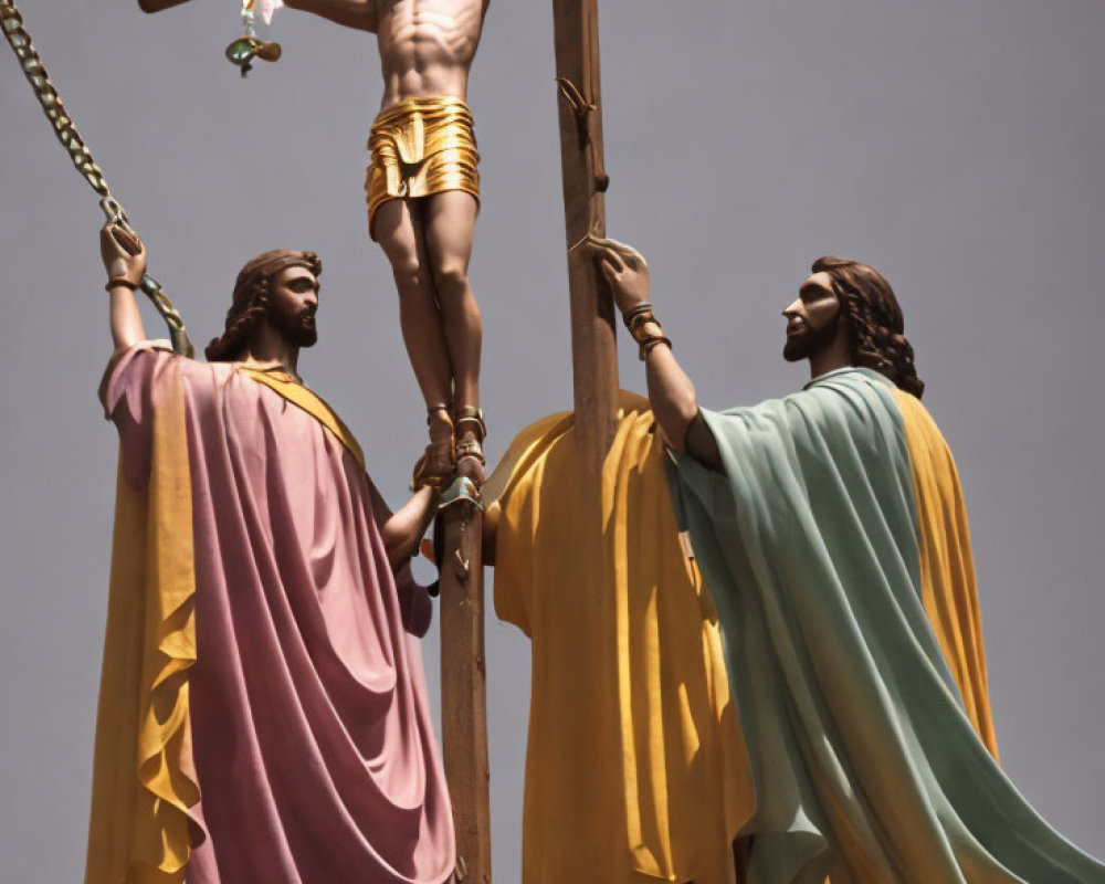 Religious statues depicting crucifixion scene with figures in robes against clear sky