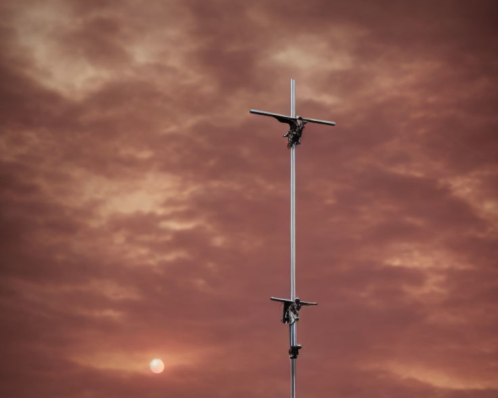 Crucifix with three figures in dramatic sunset sky