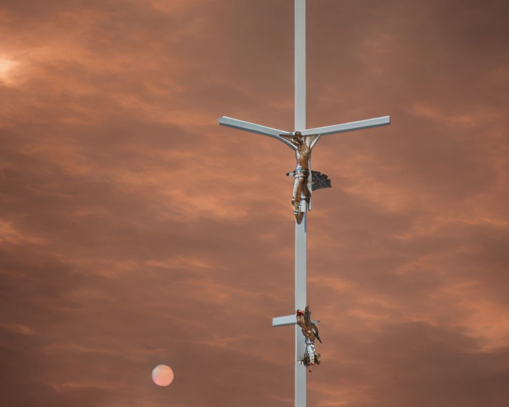 Crucifix with figures ascending against cloudy orange sky