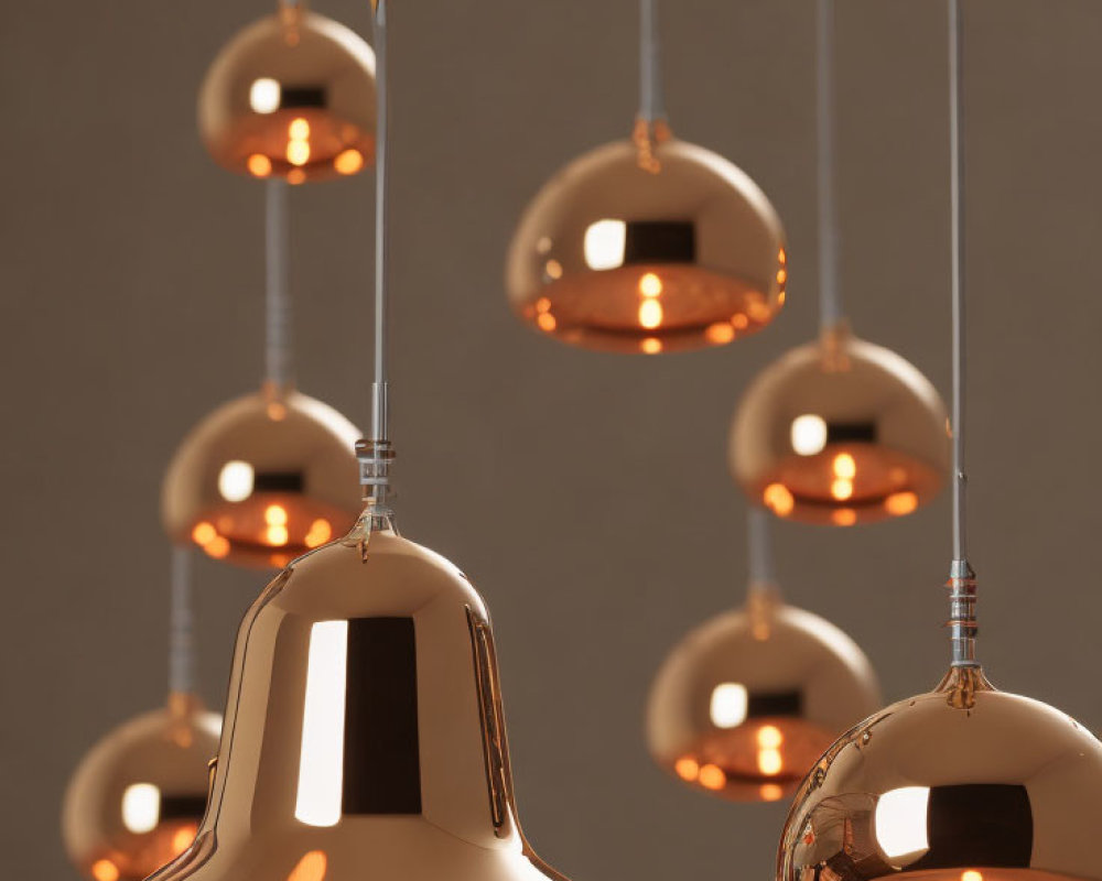 Contemporary gold pendant lights in varying heights on neutral backdrop