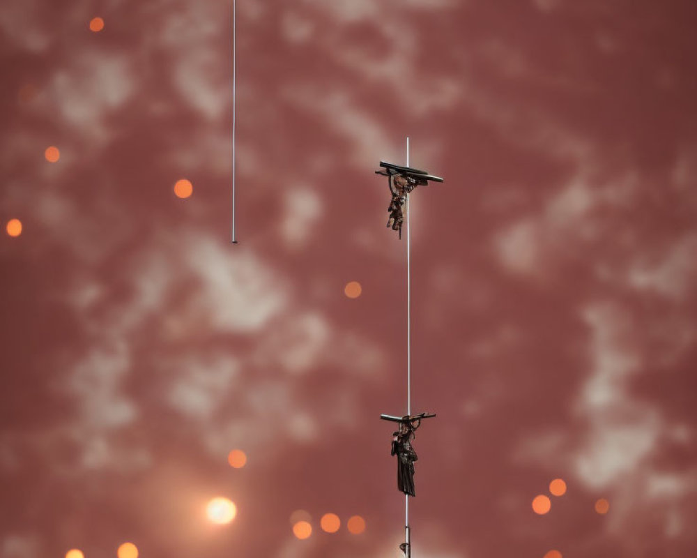 Three street lamps under cloudy reddish sky with bokeh lights, one with birds perched.