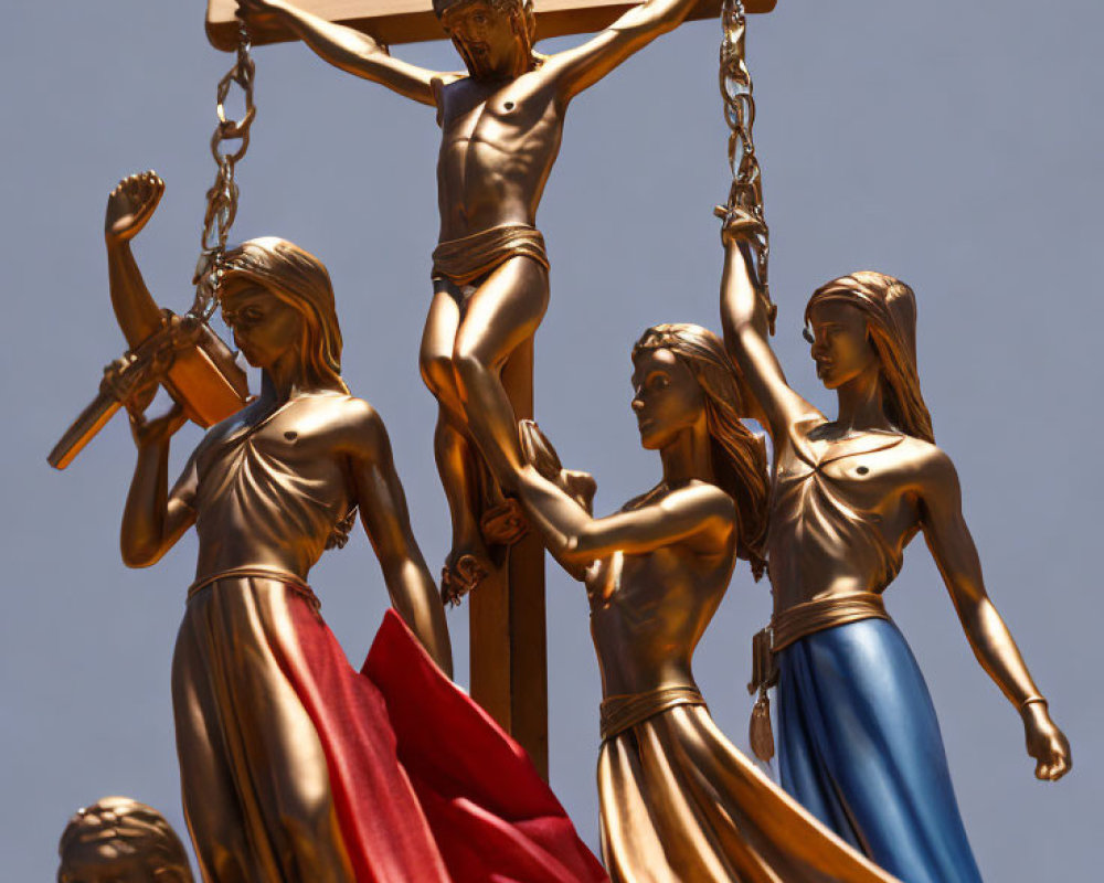 Religious sculpture of Jesus on cross with female figures under blue sky