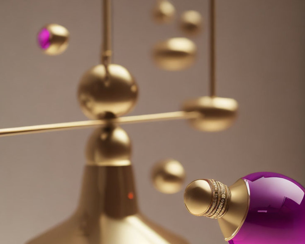 Metallic gold rods and spheres with purple glass orb in modern mobile sculpture