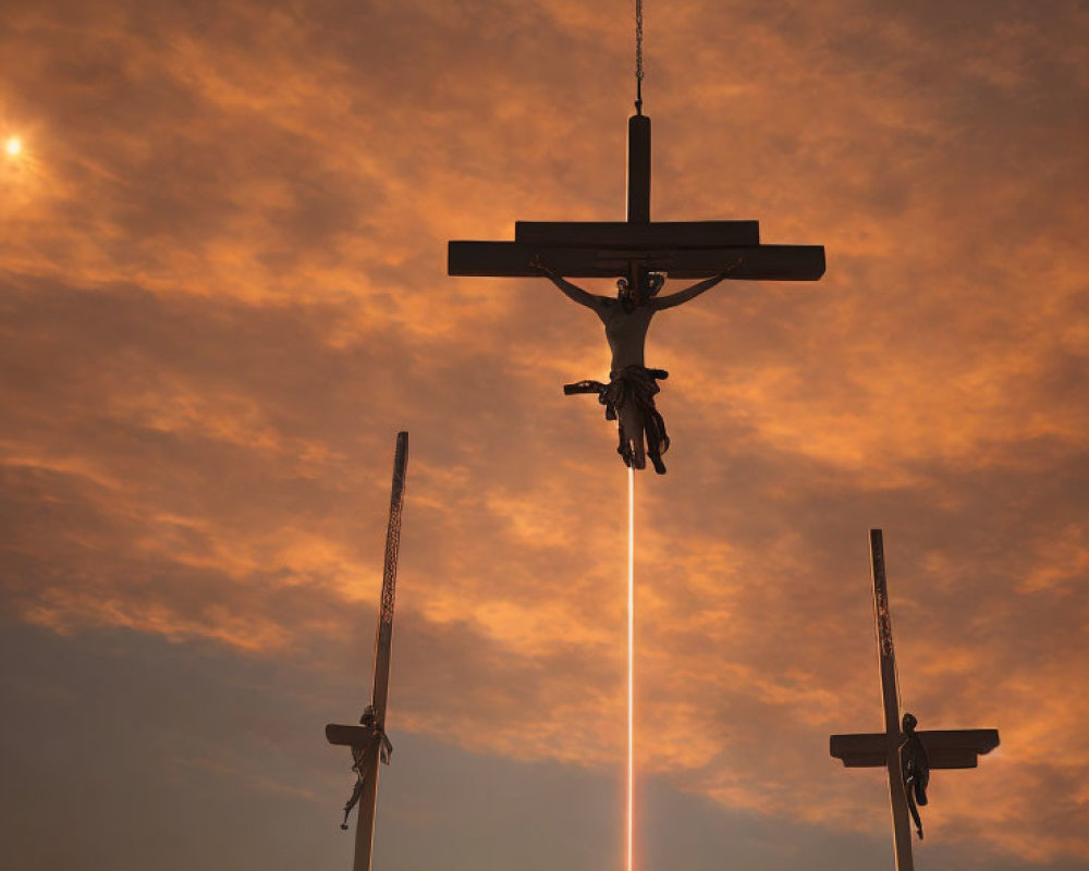 Silhouetted crosses against orange sky with Jesus figure and beam of light