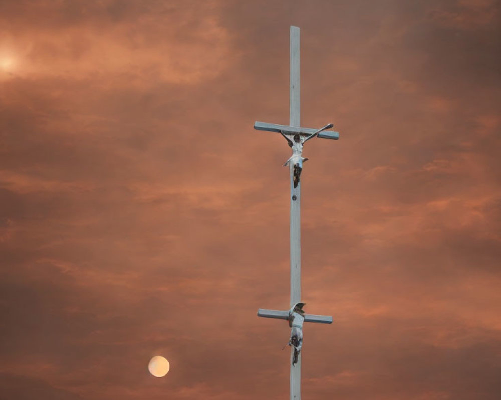 Religious crucifix with three figures under orange sky and moon