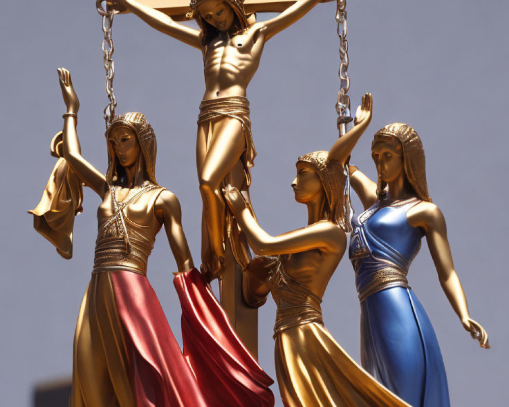 Golden statue of three figures in flowing robes supporting a fourth on a cross