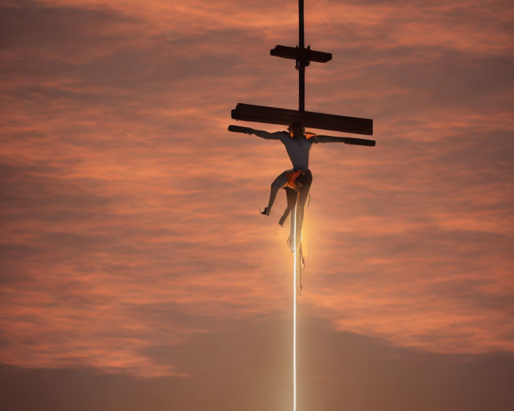 Person suspended on cross-shaped structure under dramatic orange sky