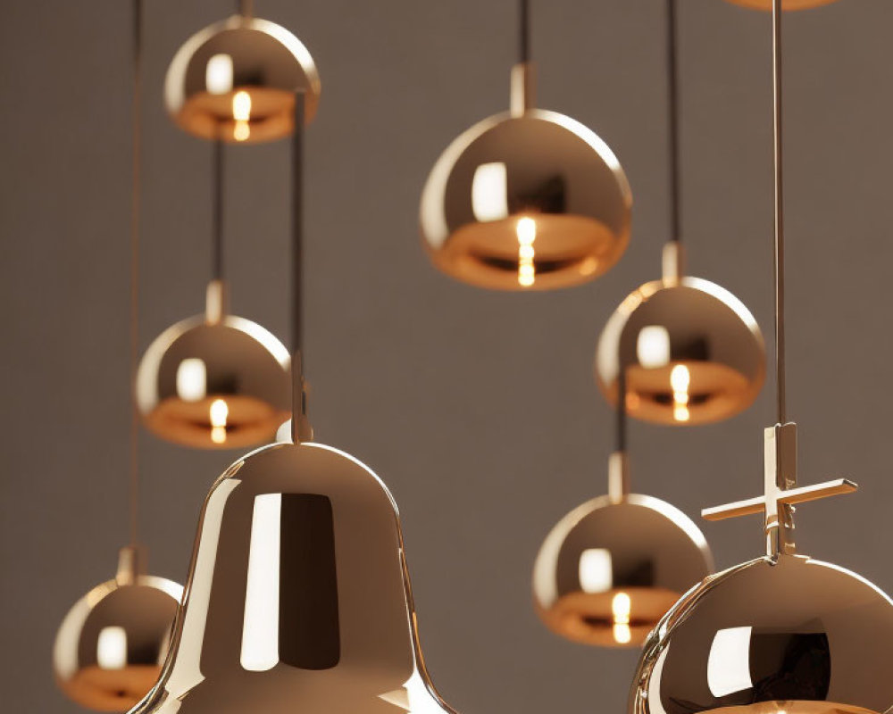 Reflective gold pendant lights at varying heights on neutral background