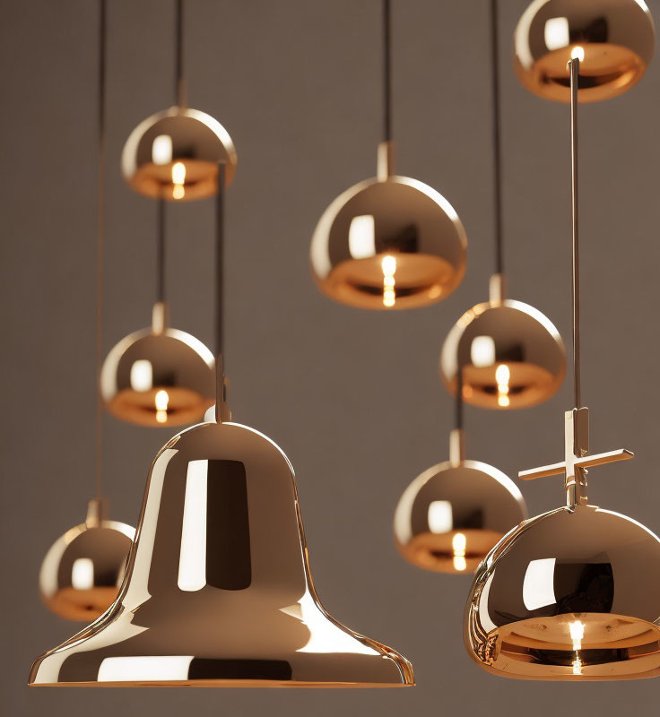 Reflective gold pendant lights at varying heights on neutral background