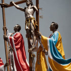 Religious statue of crucified figure in golden shorts with two robed figures in red and blue under