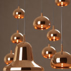 Contemporary gold pendant lights in varying heights on neutral backdrop