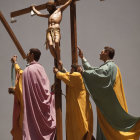 Three statues of biblical scene with figures looking up at cross