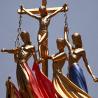 Golden statues of female figures symbolizing justice with scales and colored drapes on blue background