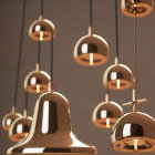 Reflective gold pendant lights at varying heights on neutral background