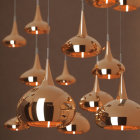 Reflective copper-toned pendant lights at varying heights on neutral backdrop