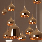 Elegant golden pendant lights in various heights on neutral backdrop