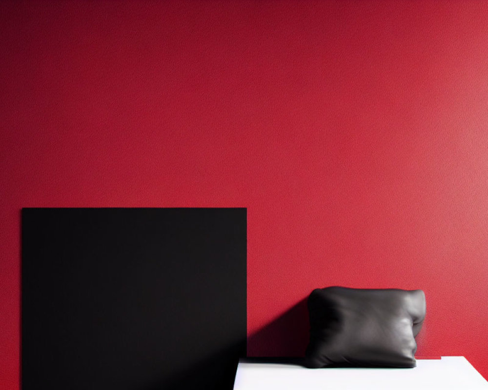 Black square canvas on white ledge with black pillow against red wall