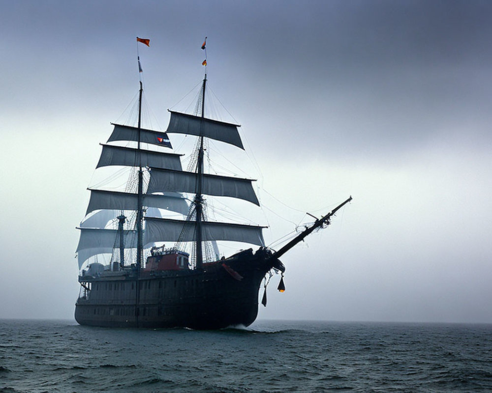 Tall ship with multiple sails on calm sea under overcast sky