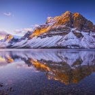 Colorful fantasy landscape with blossoming hillside, reflective water, and castle at twilight