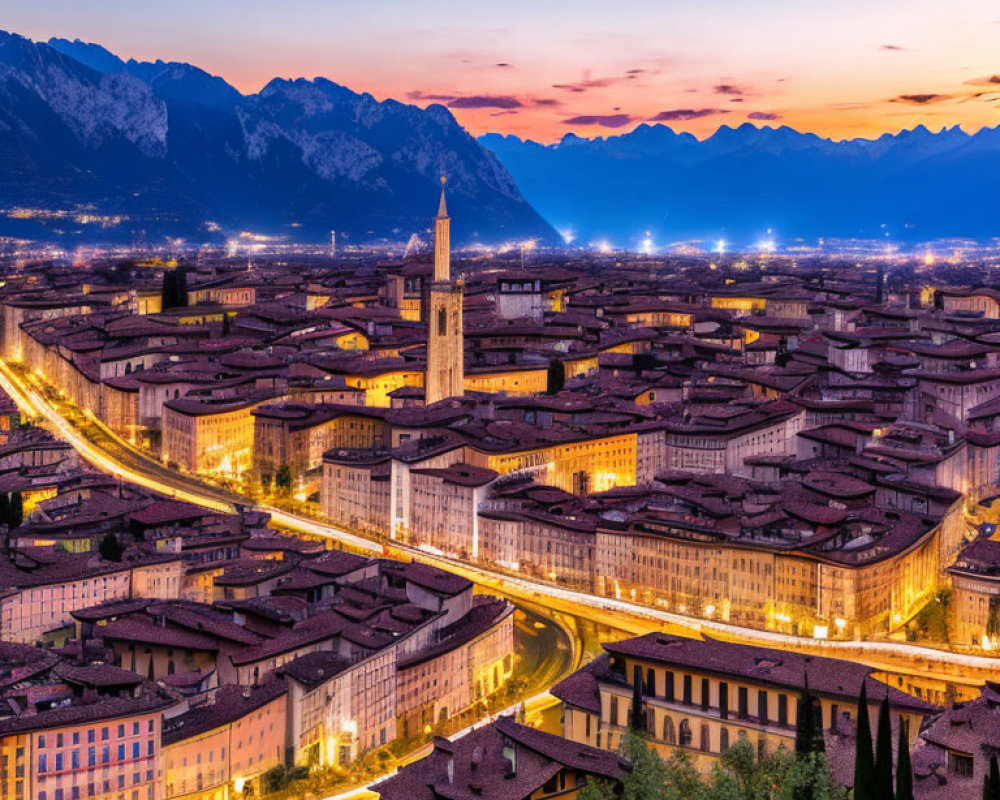 Panoramic evening view of historic city with lit streets and mountain backdrop