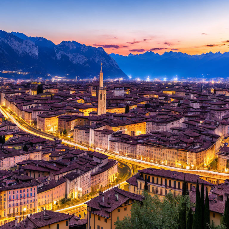 Panoramic evening view of historic city with lit streets and mountain backdrop