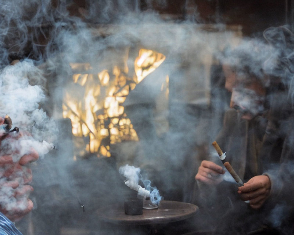 Two people in smoke with one exhaling and the other holding a smoldering object against blurred warm