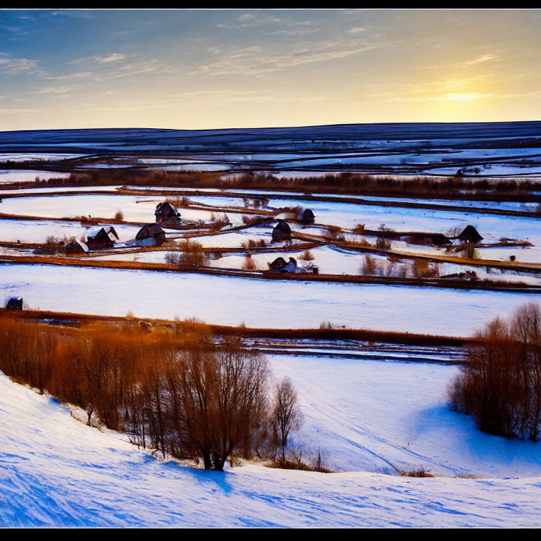 Snow-covered rural landscape with farms and winding roads at sunset