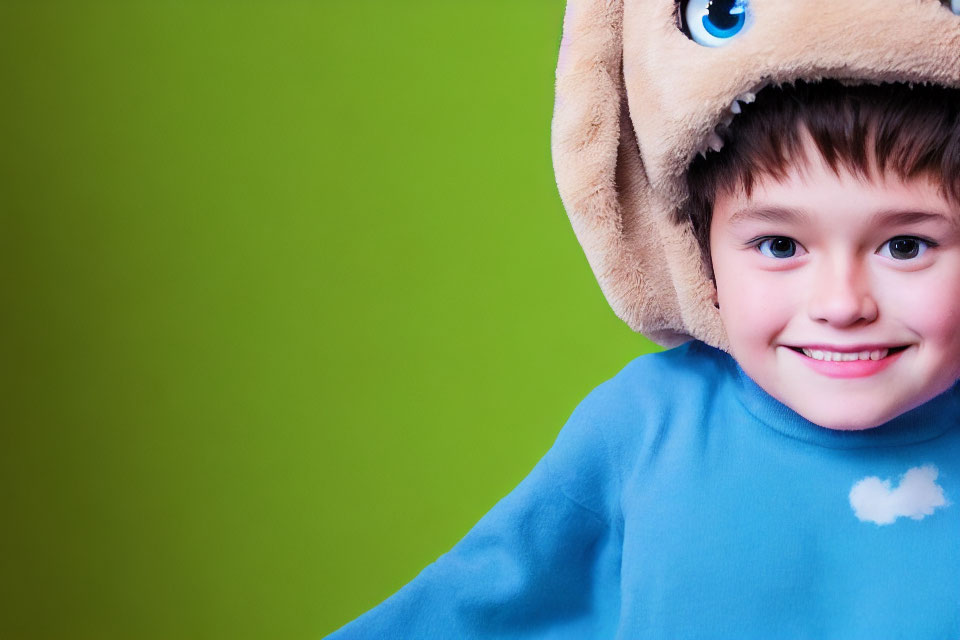 Child in Blue Shirt Wearing Bear Hat on Green Background