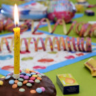 Colorful birthday candles among vibrant party decorations with balloons, confetti, and garlands.