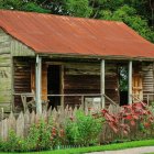 Weathered wooden cabin with rusted metal roof in serene wooded landscape