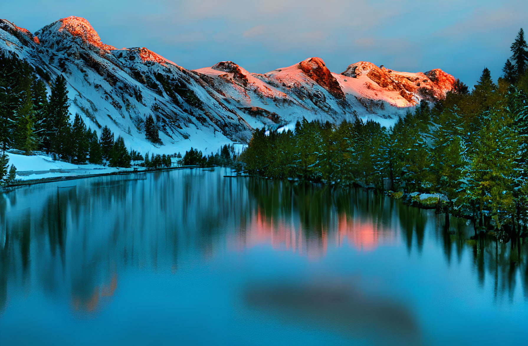 Scenic snowy mountain peaks at sunset reflected in tranquil lake