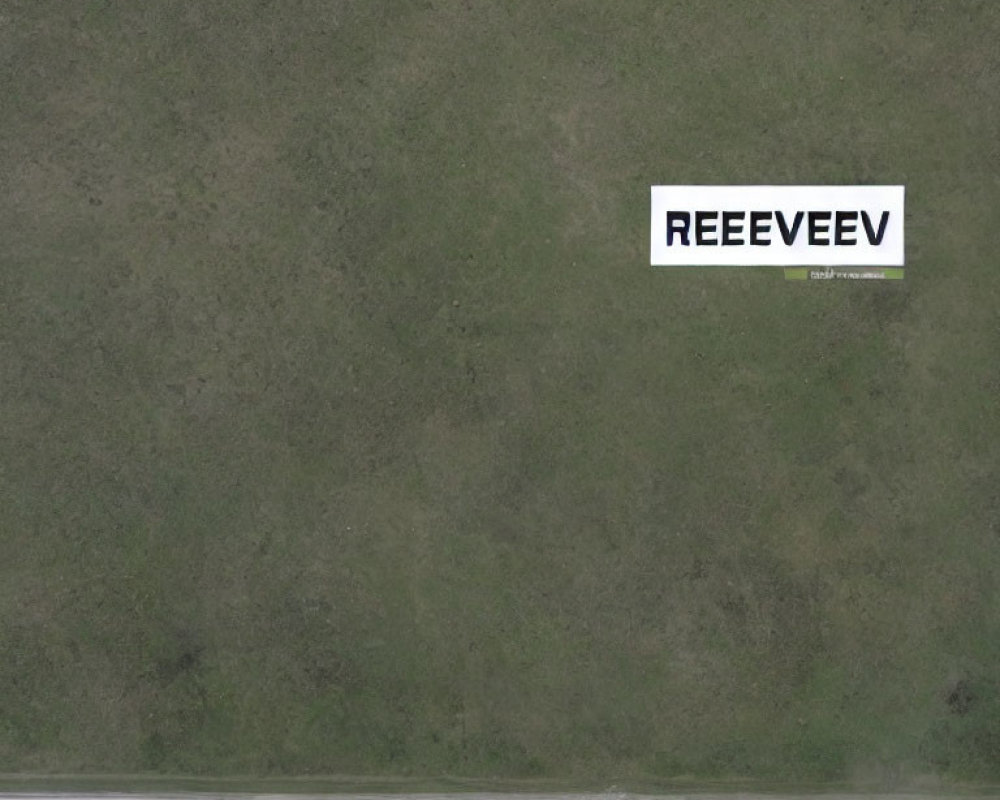 Aerial View of Green Grass Field with White Sign and Road