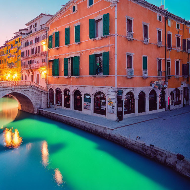 Serene Venice canal at twilight with illuminated bridge and colorful buildings