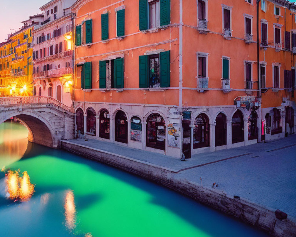 Serene Venice canal at twilight with illuminated bridge and colorful buildings