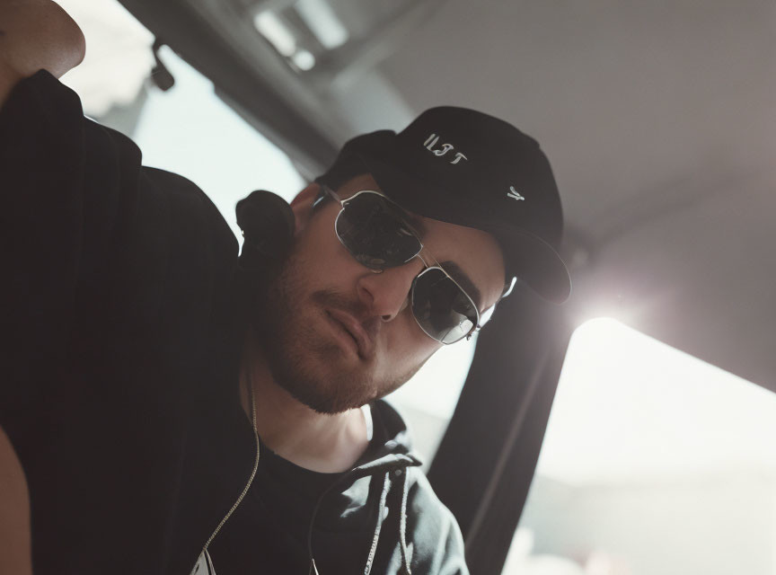 Man in sunglasses and baseball cap leaning into frame with soft sunlight glow