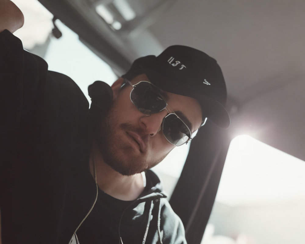 Man in sunglasses and baseball cap leaning into frame with soft sunlight glow