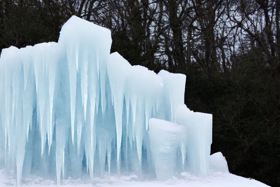 Slender ice formations resembling frozen waterfalls in a dark winter landscape