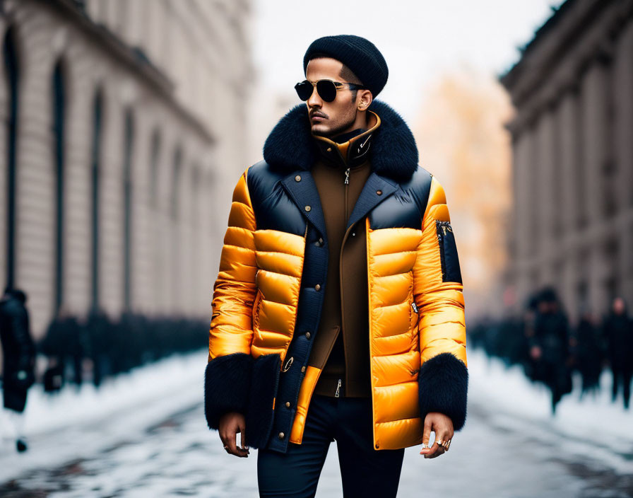 Fashionable individual in orange puffer jacket, sunglasses, beanie, and gloves walking in city.