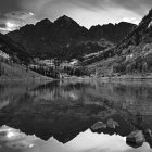 Serene monochrome landscape of lake, mountains, and forests under cloud-streaked sky