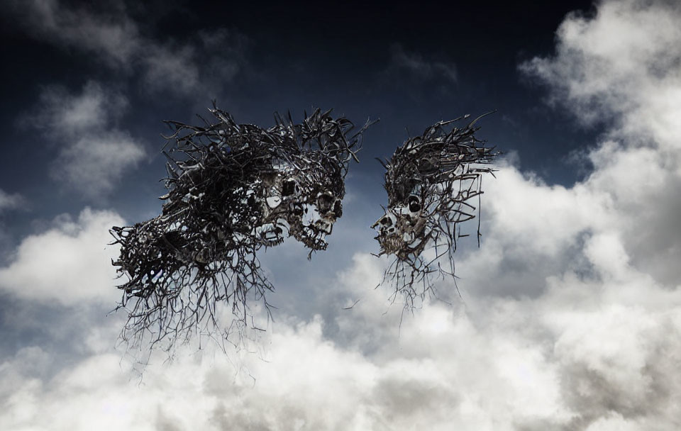 Metal sculptures of human faces against cloudy sky.