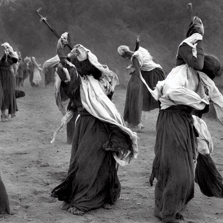 Energetic dancers in tattered garments swing staffs in dusty area