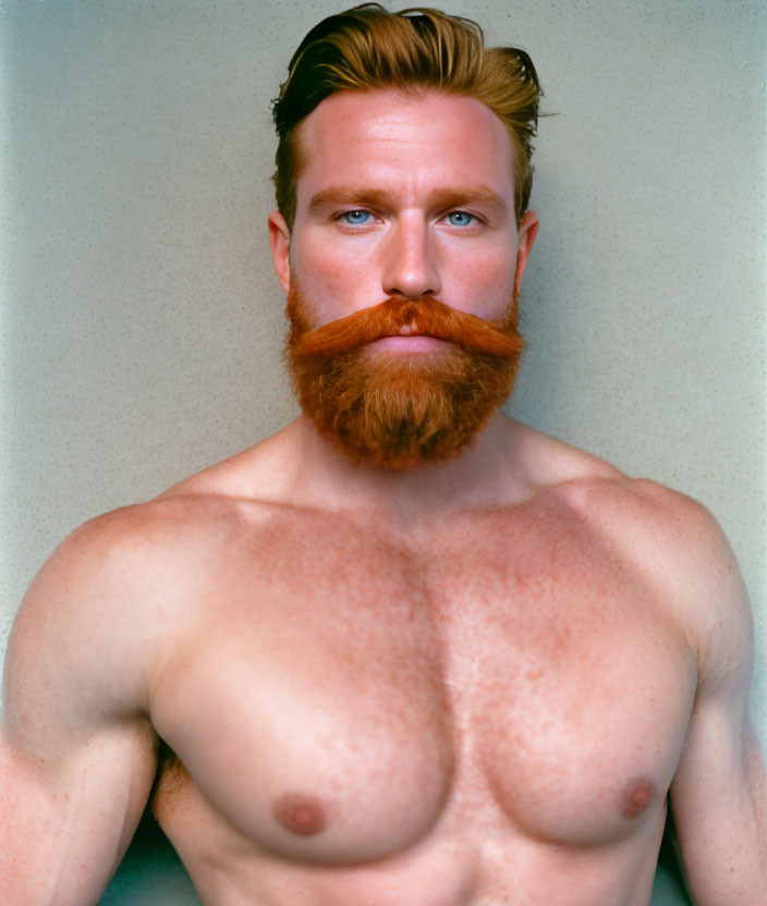 Muscular shirtless man with red beard on neutral background