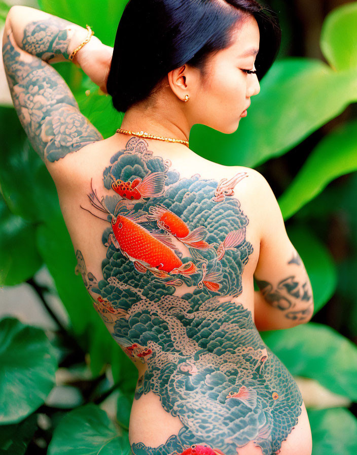 Colorful Koi Fish Tattoo on Person's Back in Green Foliage