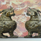 Bronze dragon sculptures on floral pattern background