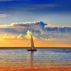 Tranquil beach scene with sailboat, crescent moon, and person sitting by shore