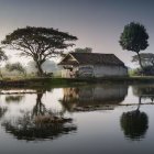 Tranquil pond reflects house and trees at dusk