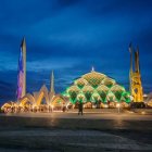 Vibrant night sky mosque with minarets and dome above illuminated town