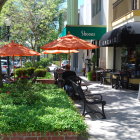 Tranquil watercolor of outdoor cafe with staircase, railing, greenery, trees, and parked