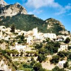 Scenic village with white houses and brown roofs on green mountain slope