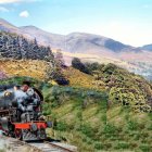 Vintage steam locomotive travels through lush countryside with mountains under blue sky